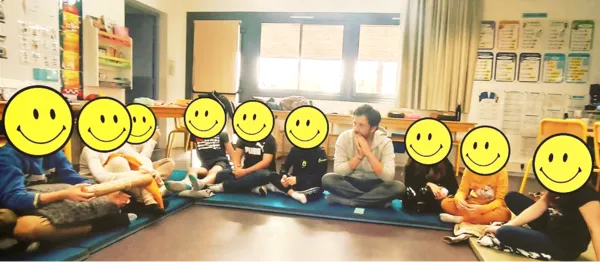 Children sitting in a circle on the classroom floor during a sharing and self-reflection workshop with Antoine Arnoult